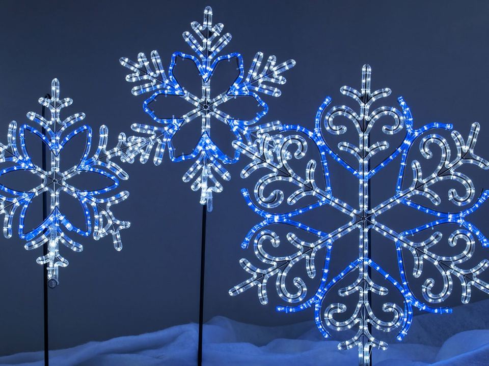 Large blue and white lit snowflakes on stakes