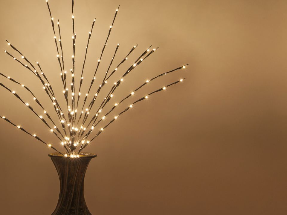 Lit branches fanning out of a vase