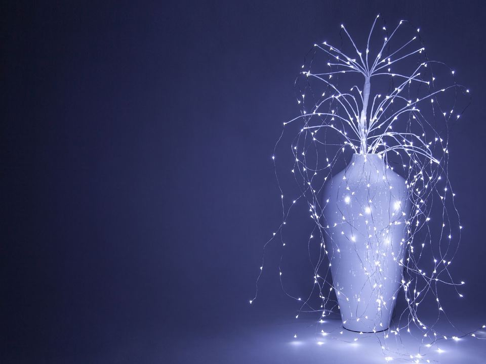 A falling willow light arching out of a white urn