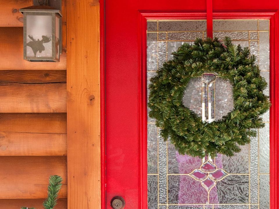A lit green wreath on a red front door