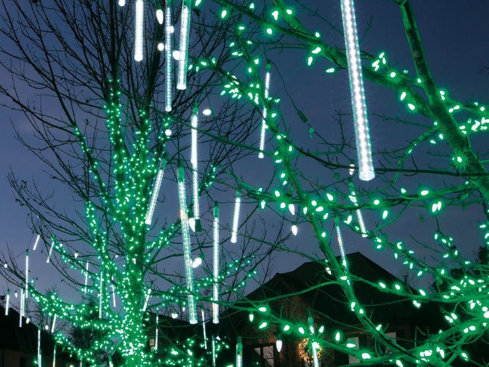 Cascade light tubes hanging in a tree wrapped in green lights