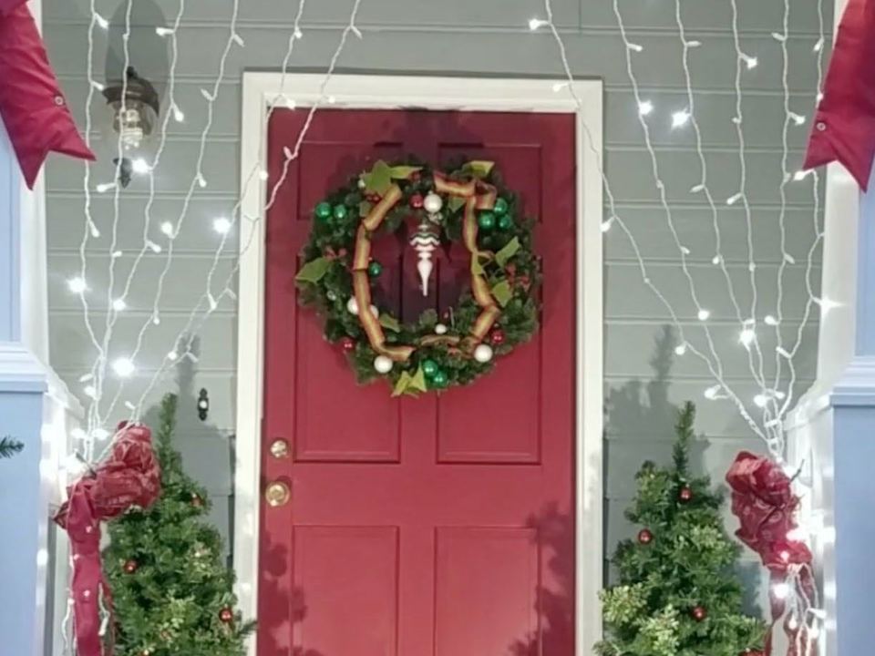 Twinkling white icicle lights framing a red front door