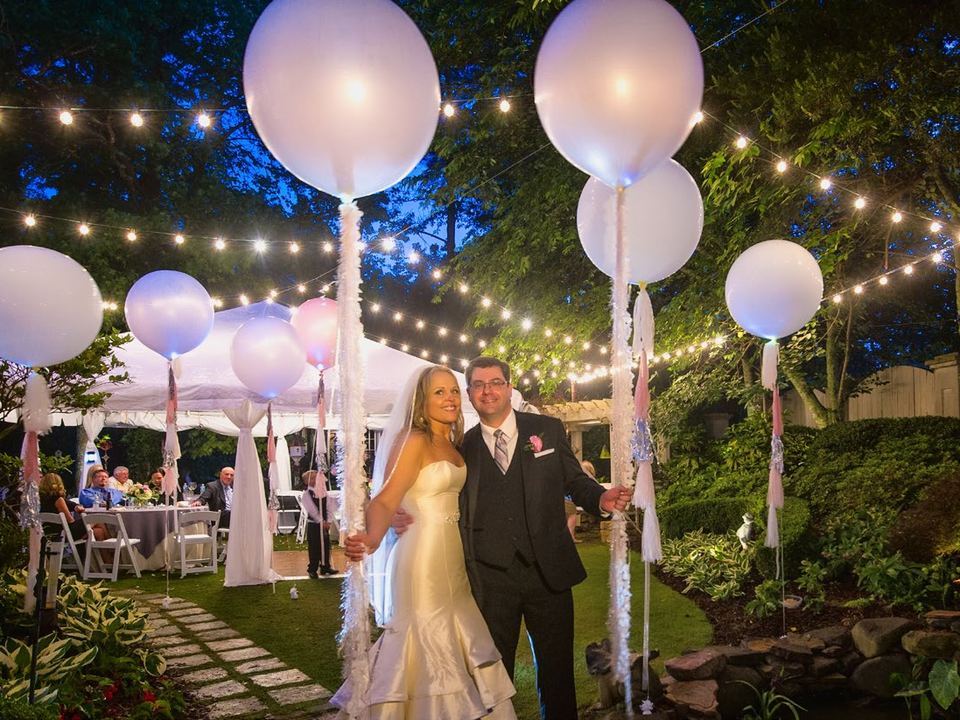 String lights and large white lit globes over an evening garden party