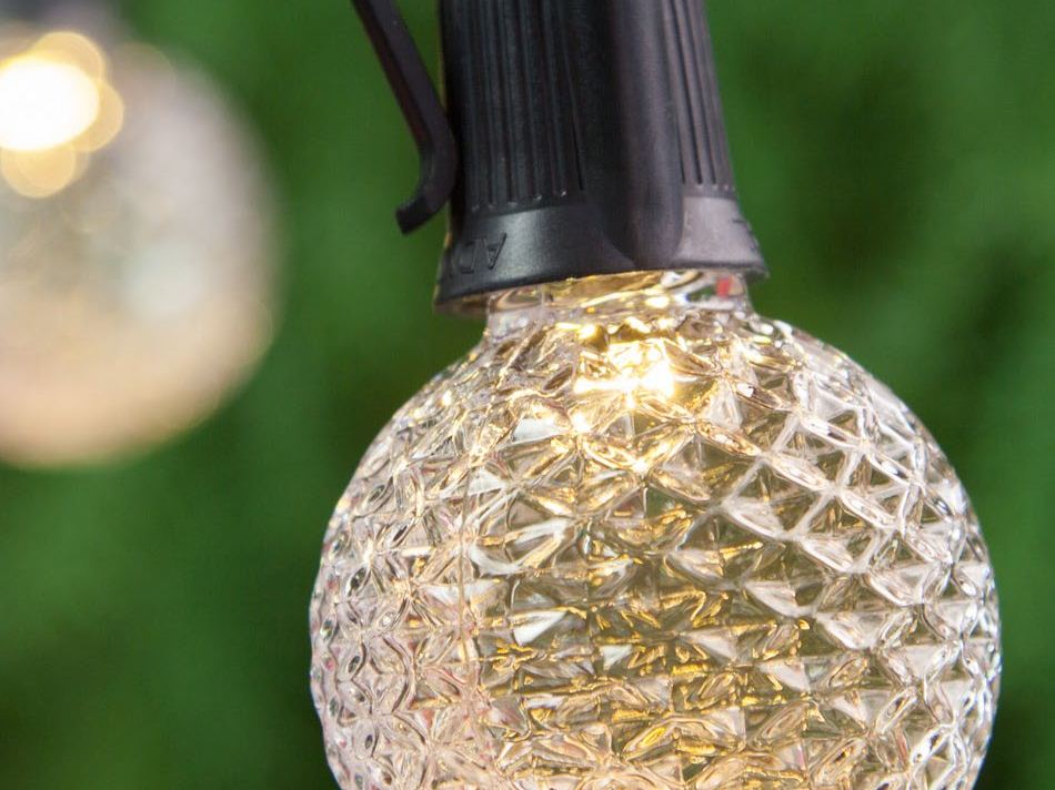 A faceted globe bulb on a string light, glowing warm white