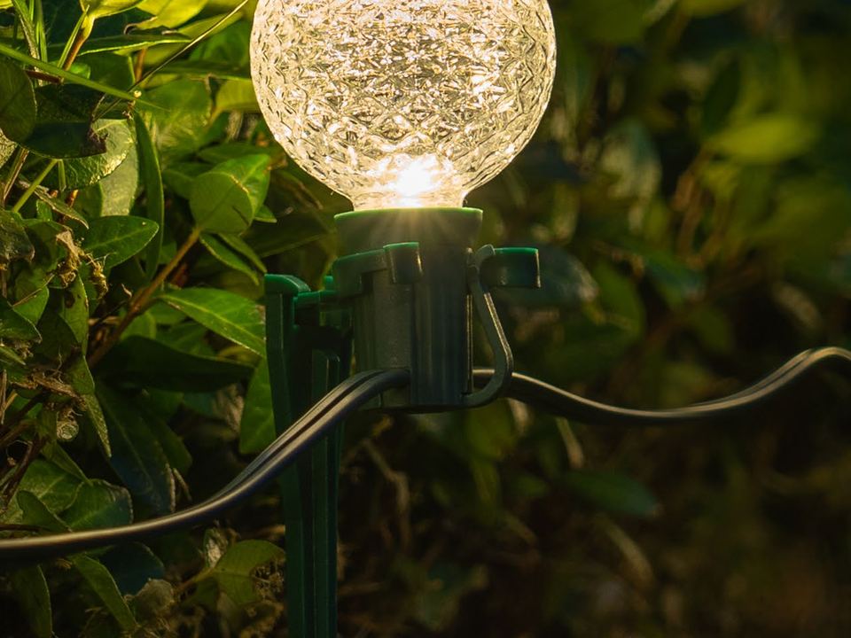 A glowing globe bulb on a stake beside a garden path