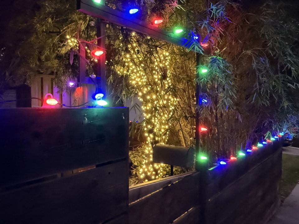 A wooden gate and fence lined with red, green and blue C9 bulbs, installed by Tater Farms