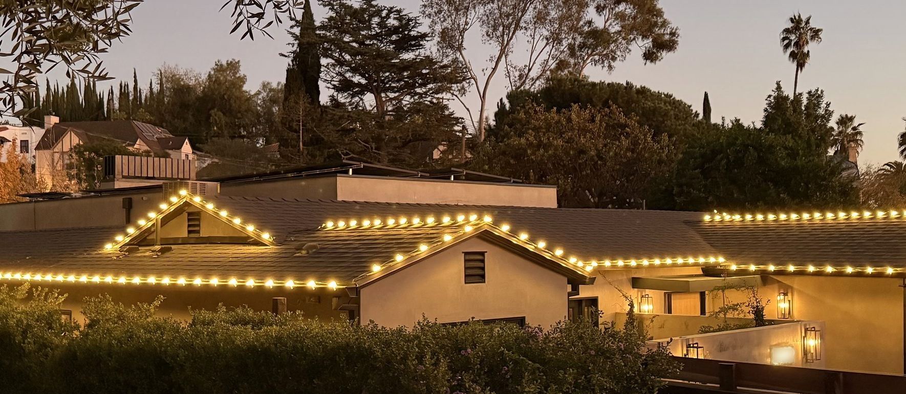A home at dusk with four gables outlined in warm white C9 lights, installed by Tater Farms