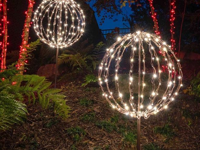 Two warm white light spheres on stakes in a garden