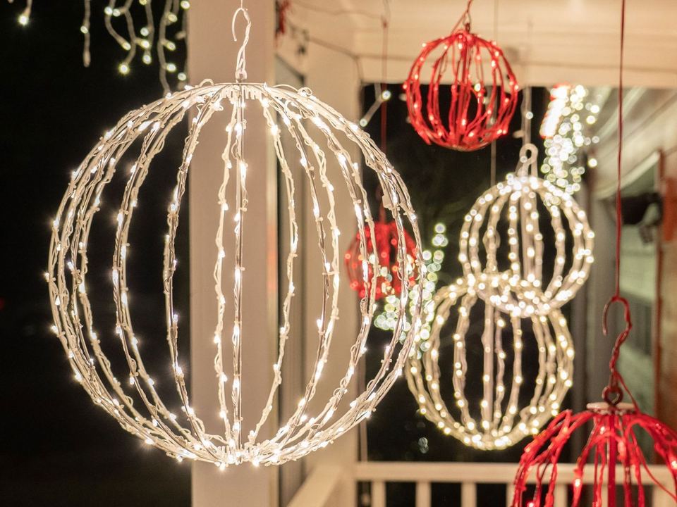 Warm white and red light spheres hanging from a porch ceiling