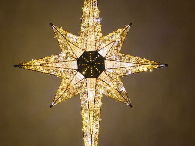 A large 8-point star covered in warm and cool white crystal lights
