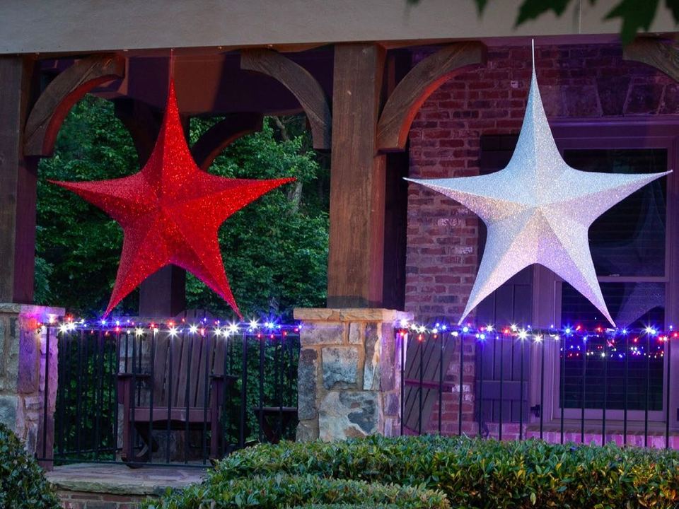 A large red fabric star and a large white fabric star hanging on a porch