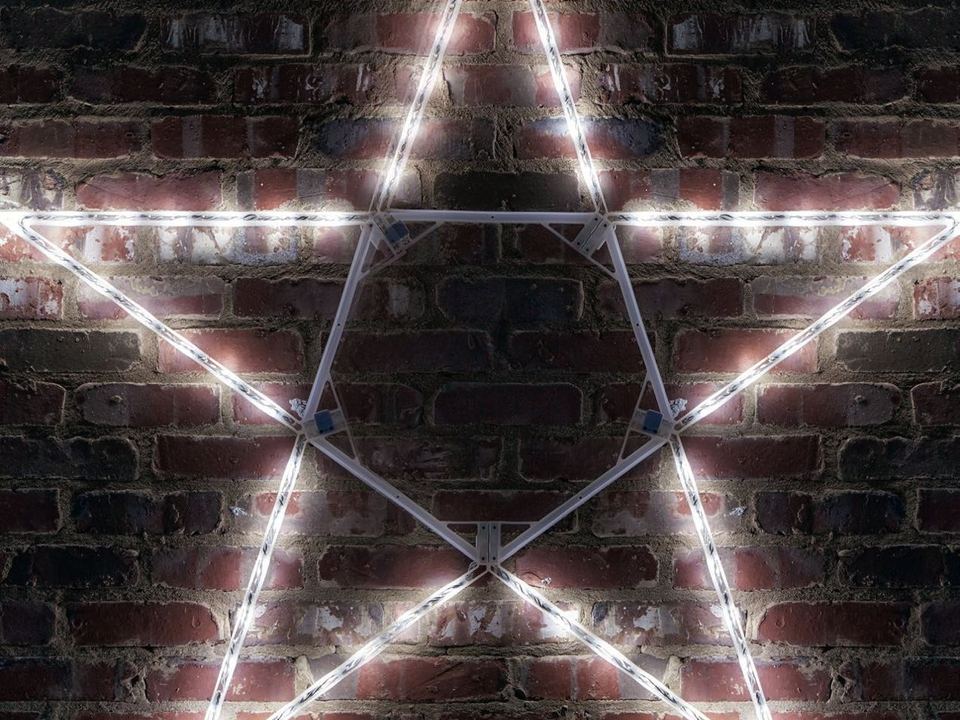 A lit white star mounted on a brick wall