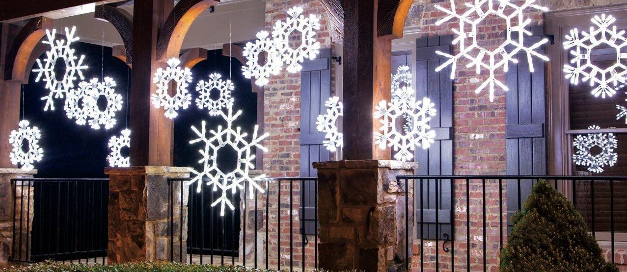 White lit snowflakes hung between the columns of a porch at night