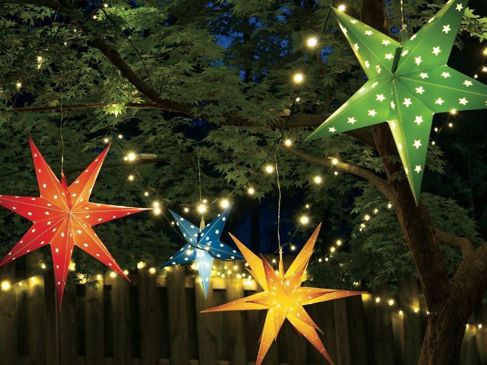 Red, gold, blue and green lantern stars hanging over a fence